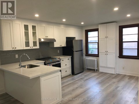 A kitchen with white cabinets and a black refrigerator.