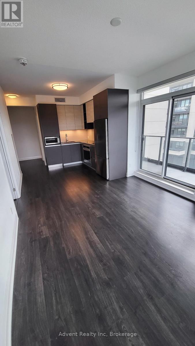 A kitchen with dark wood floors and a large window.