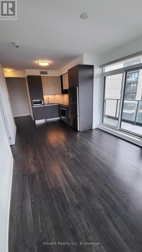 A kitchen with dark wood floors and a large window.