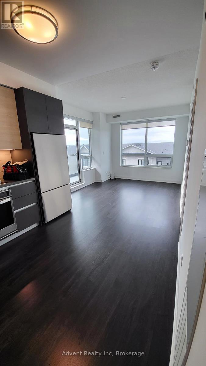 A spacious kitchen with dark wood floors and white cabinetry.