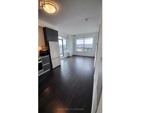 A spacious kitchen with dark wood floors and white cabinetry.
