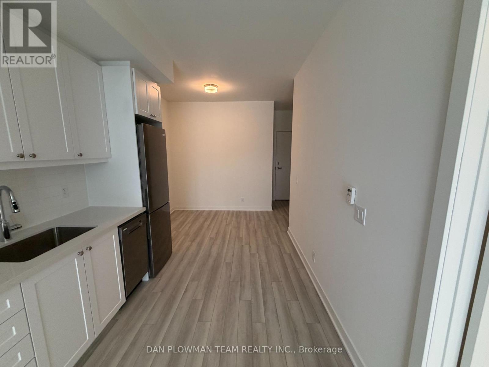 A kitchen with white cabinets and a wooden floor.