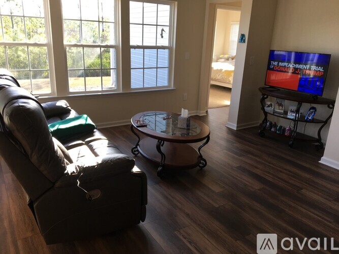 A living room with a couch, chair, and a television displaying "The Impeachment Trial of Donald Trump".