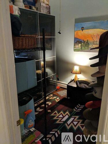 A room with a rug, a lamp, and a painting on the wall.