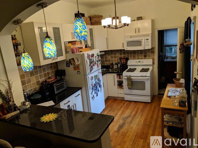 A kitchen with a black counter top and white appliances.