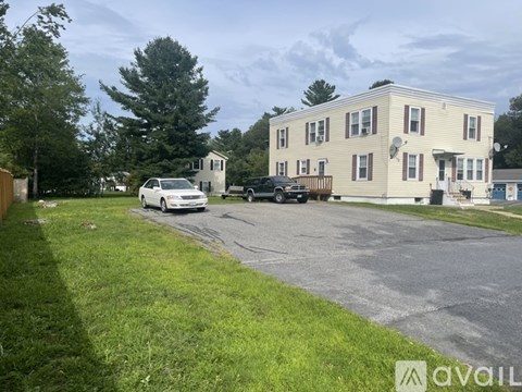 A white car is parked in front of a two-story house.