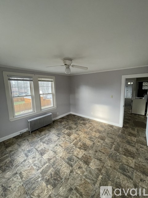 A room with a ceiling fan and a window with a view of a fence and trees.