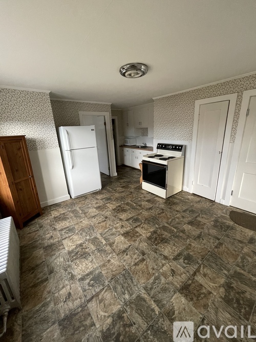 A kitchen with a white fridge, white oven, and a tiled floor.