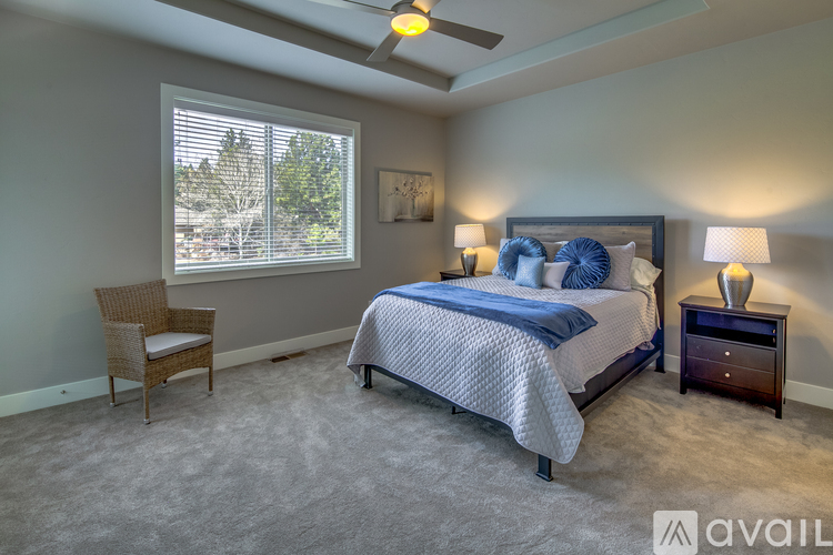 A bedroom with a bed, chair, and window.