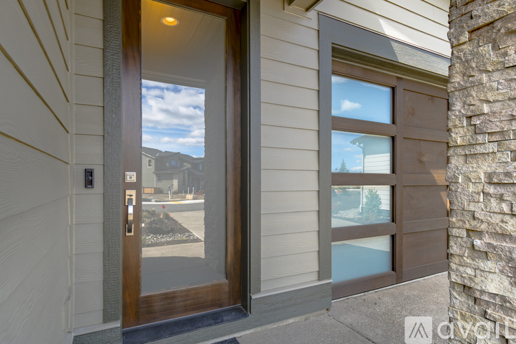 A modern house entrance with a glass door and a stone pillar.