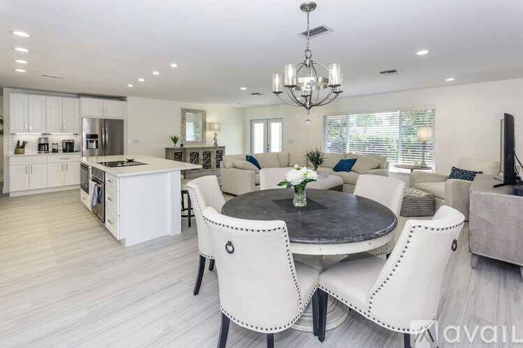 A modern dining room with a round table and white chairs.
