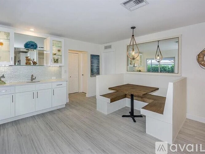 A modern kitchen with a wooden table and white cabinets.