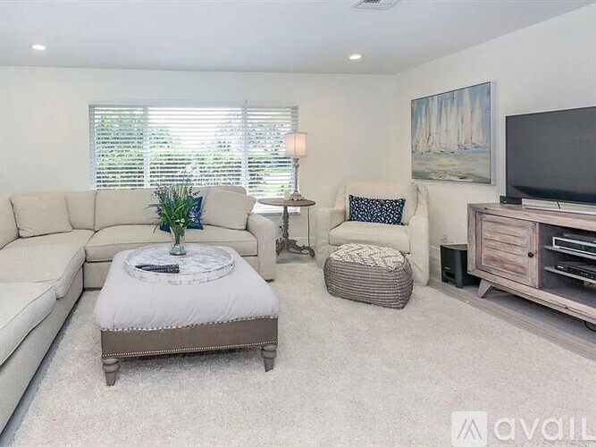 A living room with a couch, ottoman, and television.