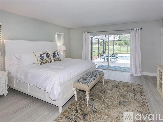 A bedroom with a large bed and a view of a pool through the window.