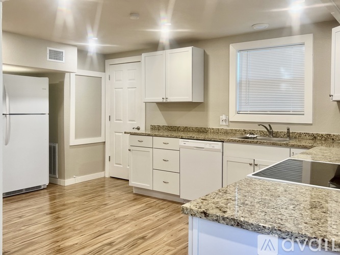 A kitchen with white cabinets and a granite countertop.