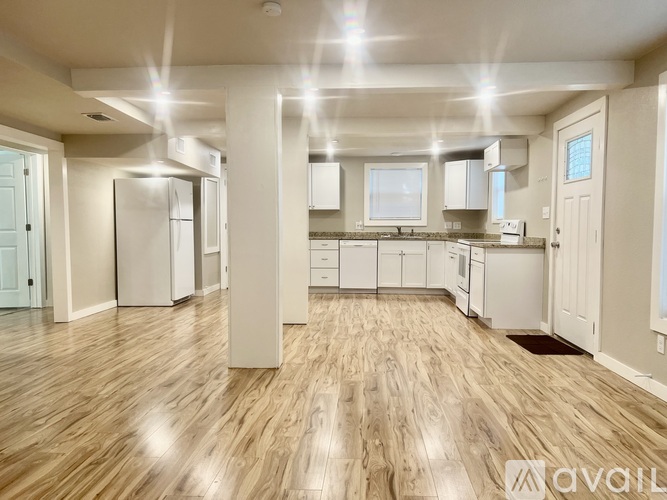 A spacious kitchen with wooden floors and white appliances.