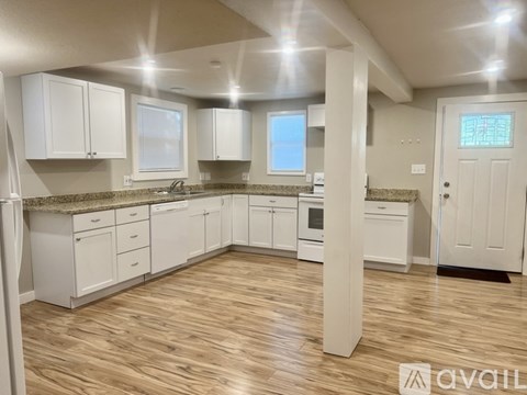 A kitchen with white cabinets and a wooden floor.