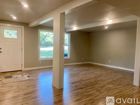 A room with wooden flooring and a white door is available for rent.