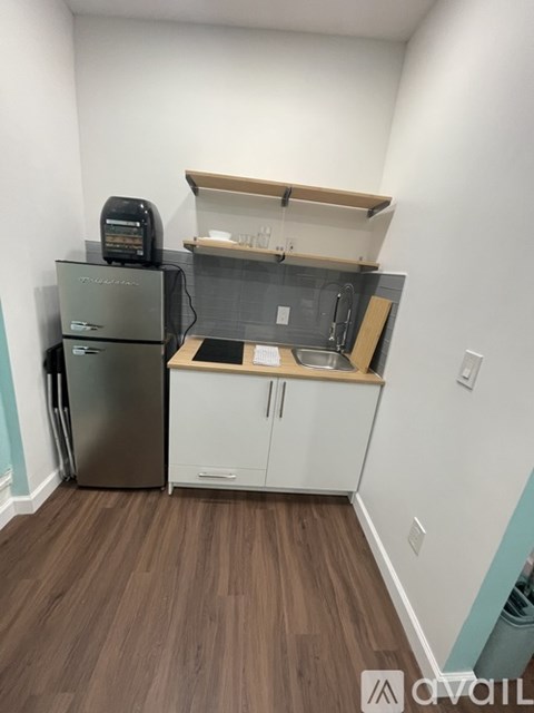 A kitchen with a refrigerator, cabinets, and a counter.