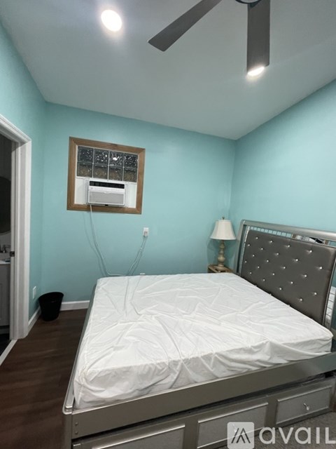 A bedroom with a bed, a ceiling fan, and a window with blinds.