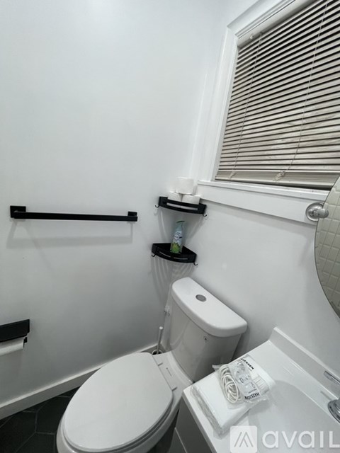 A white toilet in a small bathroom with a towel rack and a towel hanging on it.