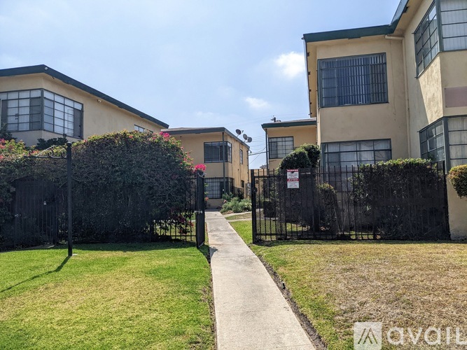 A black fence surrounds a green lawn in front of a building.