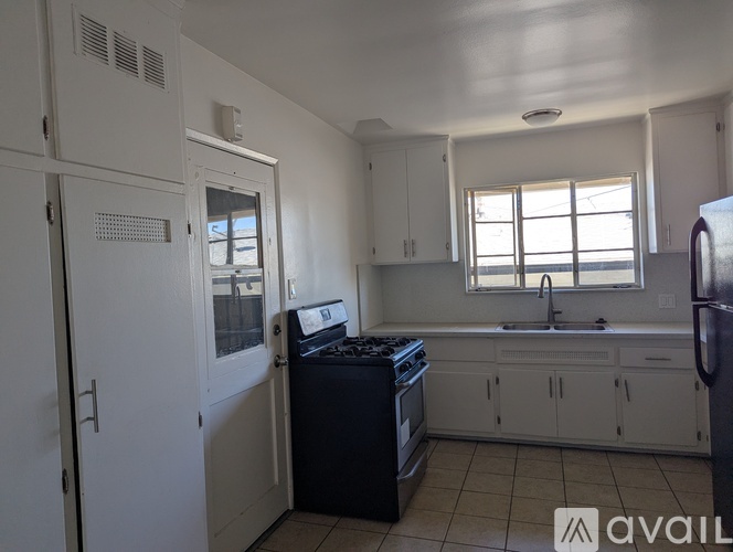 A kitchen with white cabinets and black appliances.