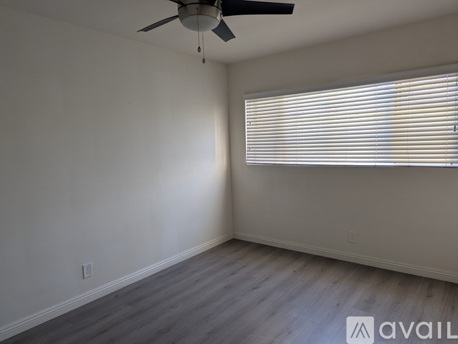 A room with a ceiling fan and a window with blinds.