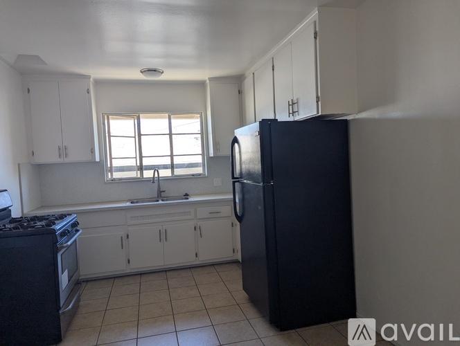 A kitchen with a black fridge and white cabinets.
