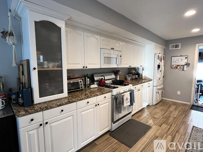A kitchen with white cabinets and a granite countertop.