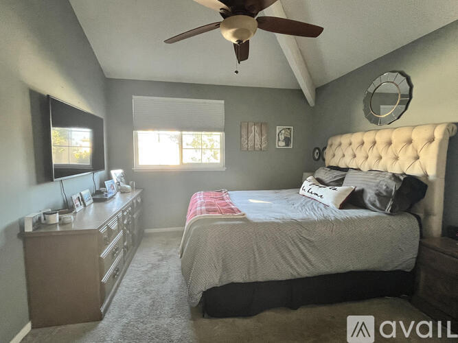 A bedroom with a bed, dresser, and ceiling fan.