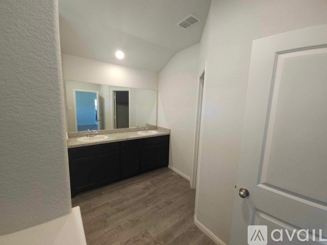 A bathroom with a white door and a mirror above the sink.