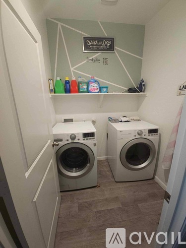 A laundry room with two washing machines and a shelf with cleaning products.