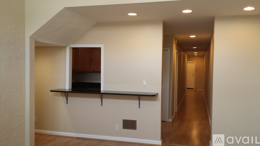 A long hallway with a cabinet and a shelf on the wall.