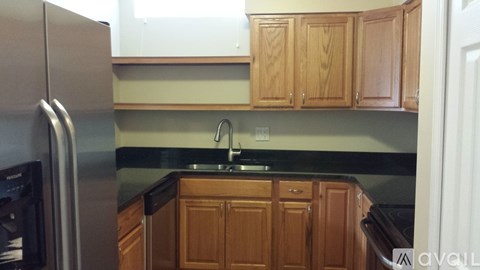 A kitchen with wooden cabinets and a black fridge.