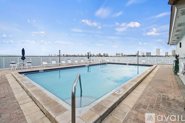 A swimming pool surrounded by a brick patio and lounge chairs.