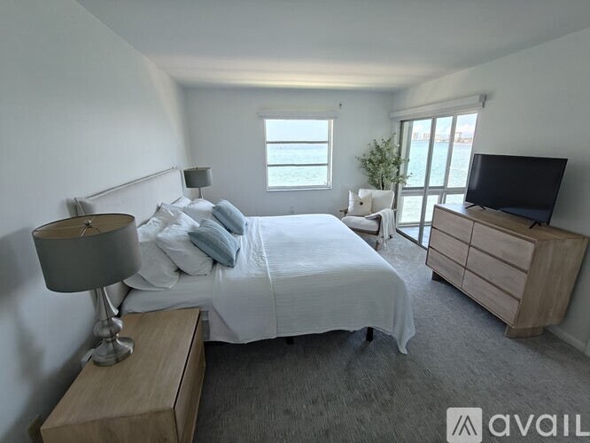 A bedroom with a large bed, a nightstand with a lamp, and a television on a dresser.