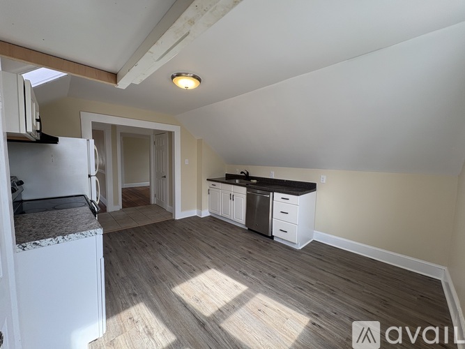 A kitchen with white appliances and wooden floors.