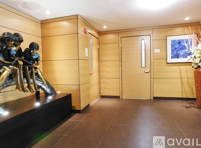 A hallway with a statue of three people and a vase of flowers on the right.