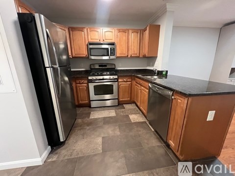 A kitchen with wooden cabinets and a black refrigerator.