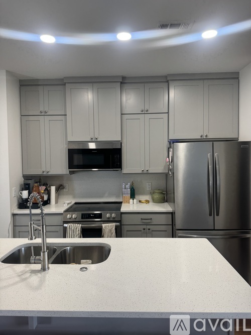 A kitchen with white cabinets and a stainless steel refrigerator.