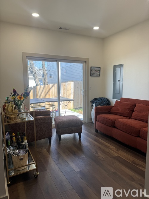 A living room with a red couch and a wooden floor.