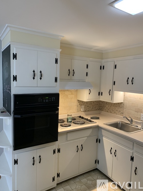 A kitchen with white cabinets and black appliances.