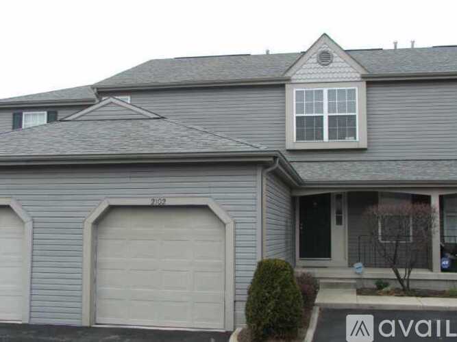 A house with a grey siding and a white garage door.