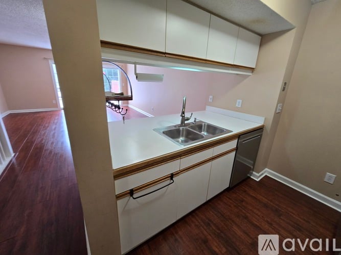 A kitchen with white cabinets and a wooden floor.