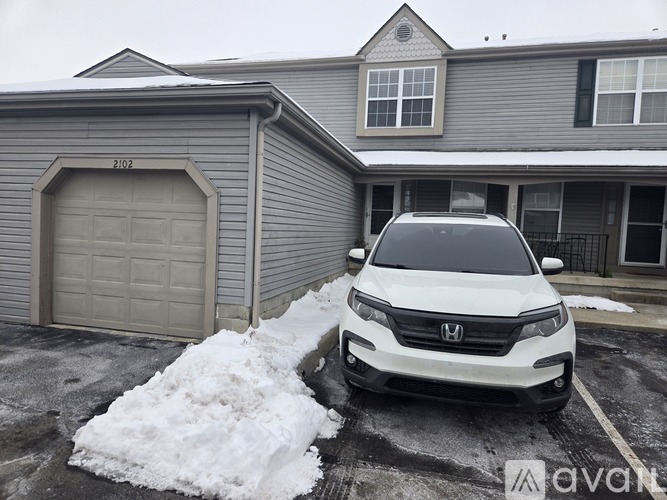 A white Honda SUV is parked in front of a grey building with a garage door.