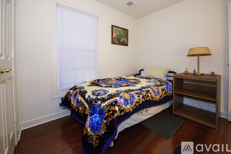 A bedroom with a floral bedspread and a wooden nightstand.