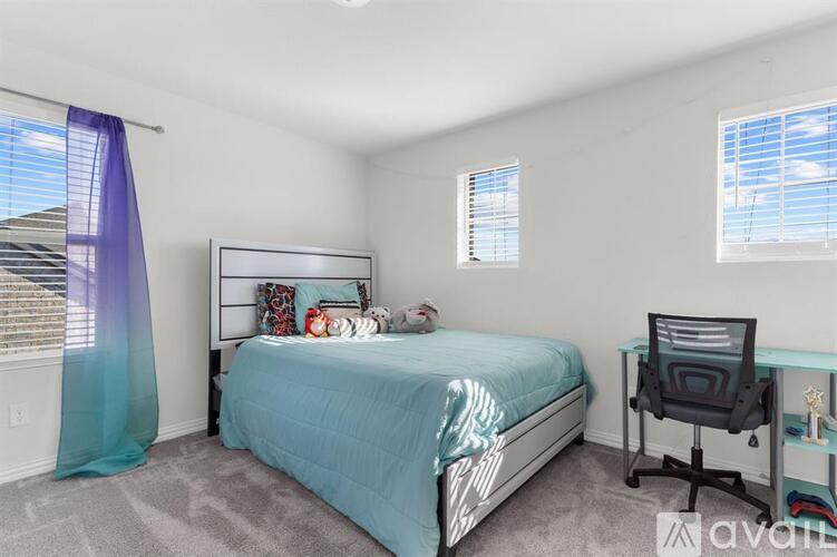 A bedroom with a bed, desk, and chair.