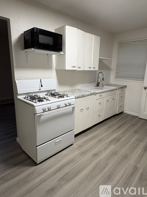 A kitchen with a white stove and cabinets.