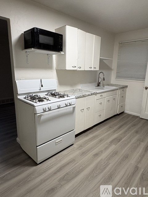 A kitchen with a white stove and cabinets.